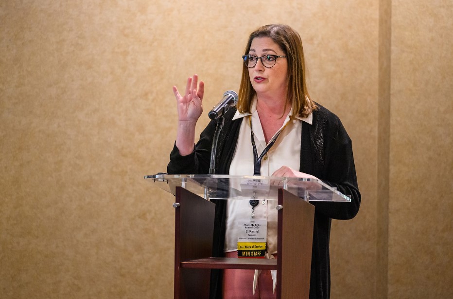 Rachel Mutrux, director of the Missouri Telehealth Network, stands behind a podium, talking at a conference.