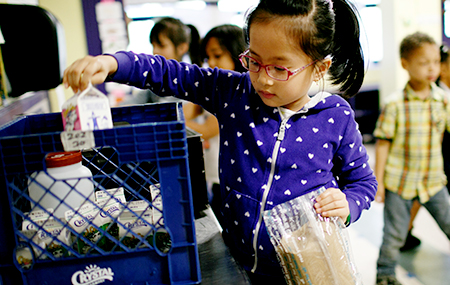 Stock photo of a student choosing a carton of milk in a school cafeteria.