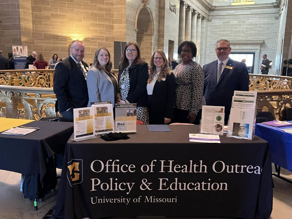 Six representatives of the Office of HOPE posing at an exhibit table in the Missouri Capitol Building.